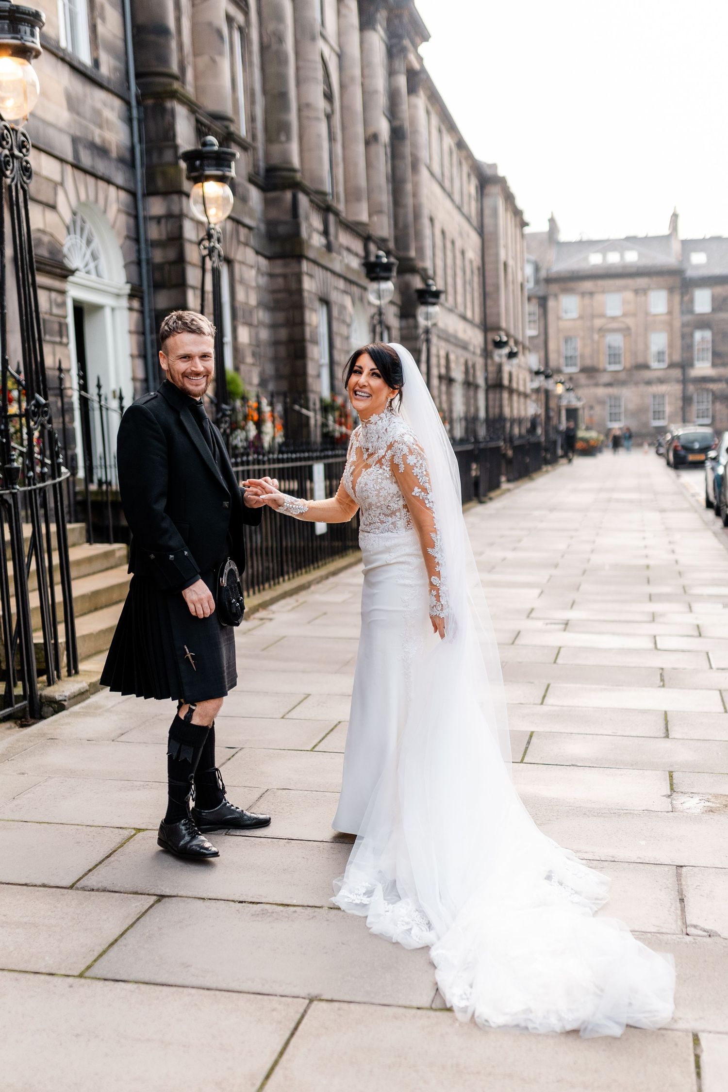 Scottish wedding couple posing on elegant Edinburgh street with traditional architecture.