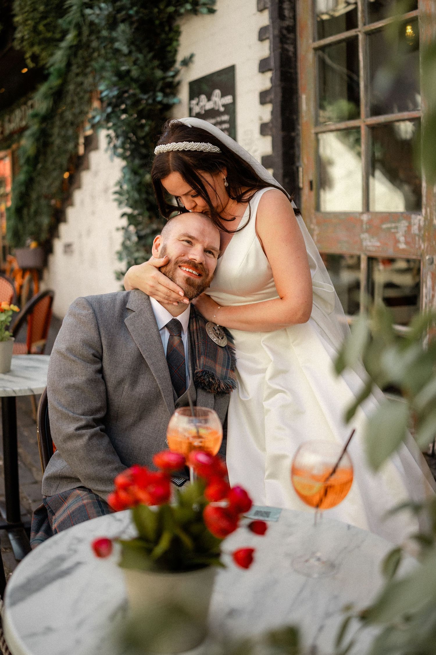 Intimate outdoor wedding reception with red flowers and cocktails on table.