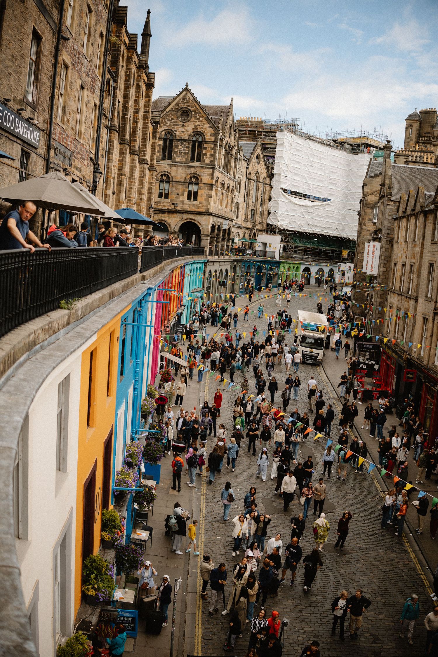 Aerial view of colorful Victoria Street in Edinburgh, Scotland, crowded with tourists during the Fringe Festival.
