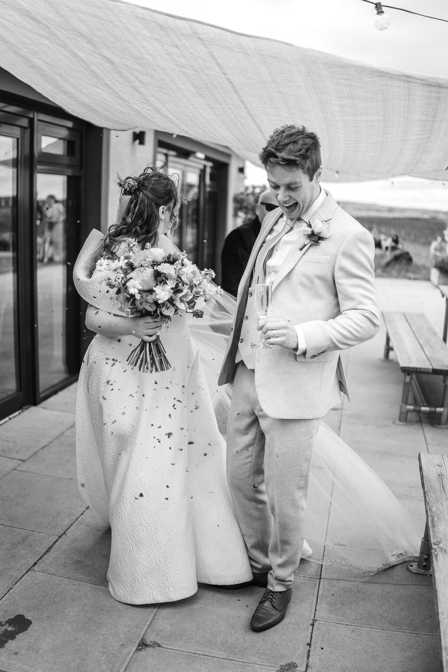 Bride and groom laughing together outdoors after their wedding ceremony.