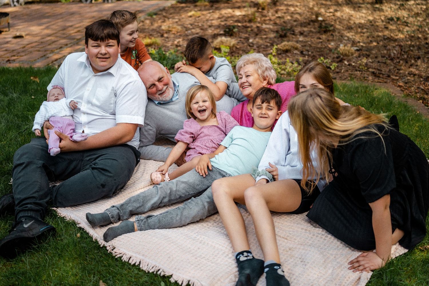 A family relaxes together on a blanket during an outdoor photo session.