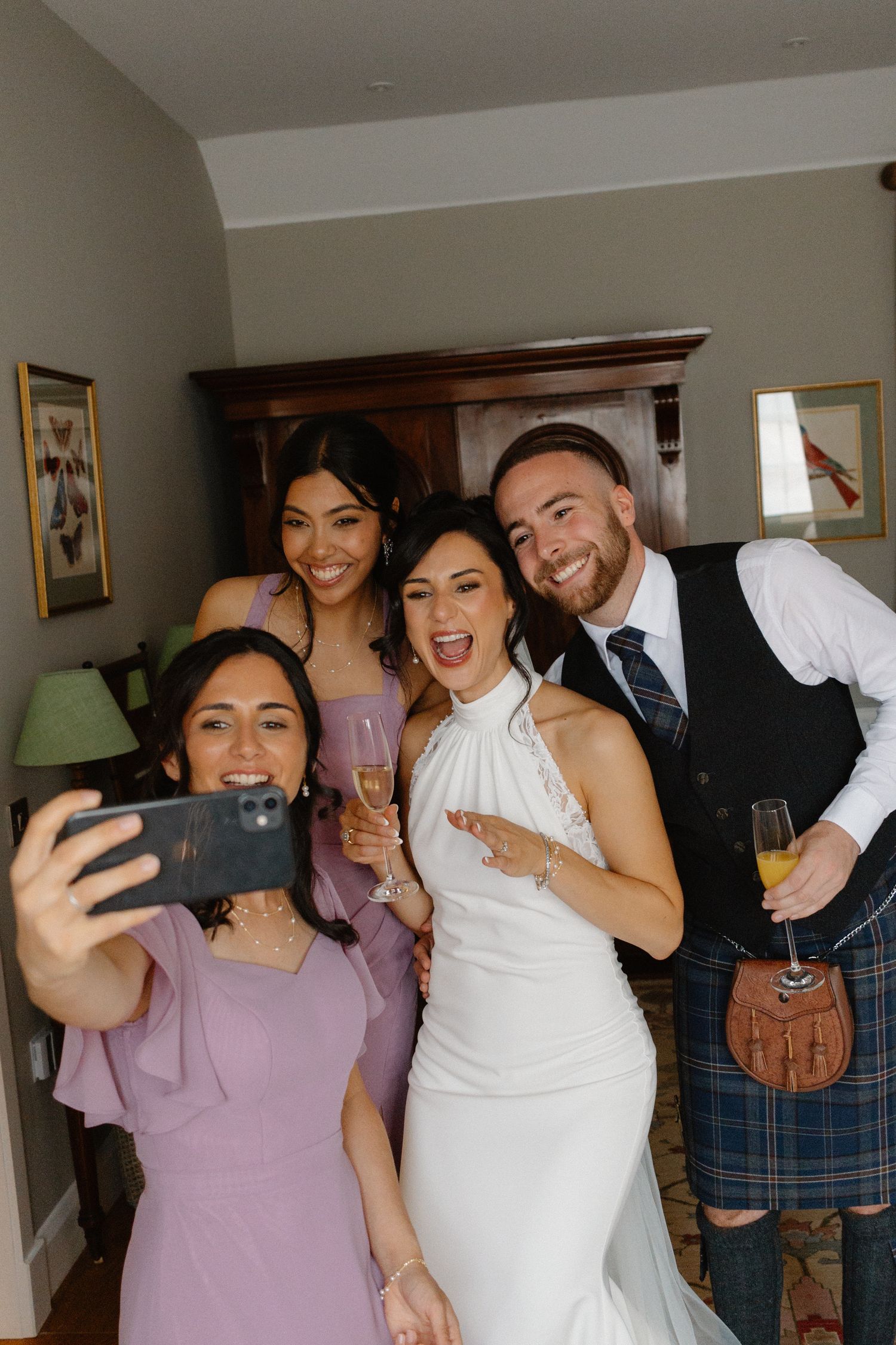 Wedding party taking selfies and laughing together in formal attire.