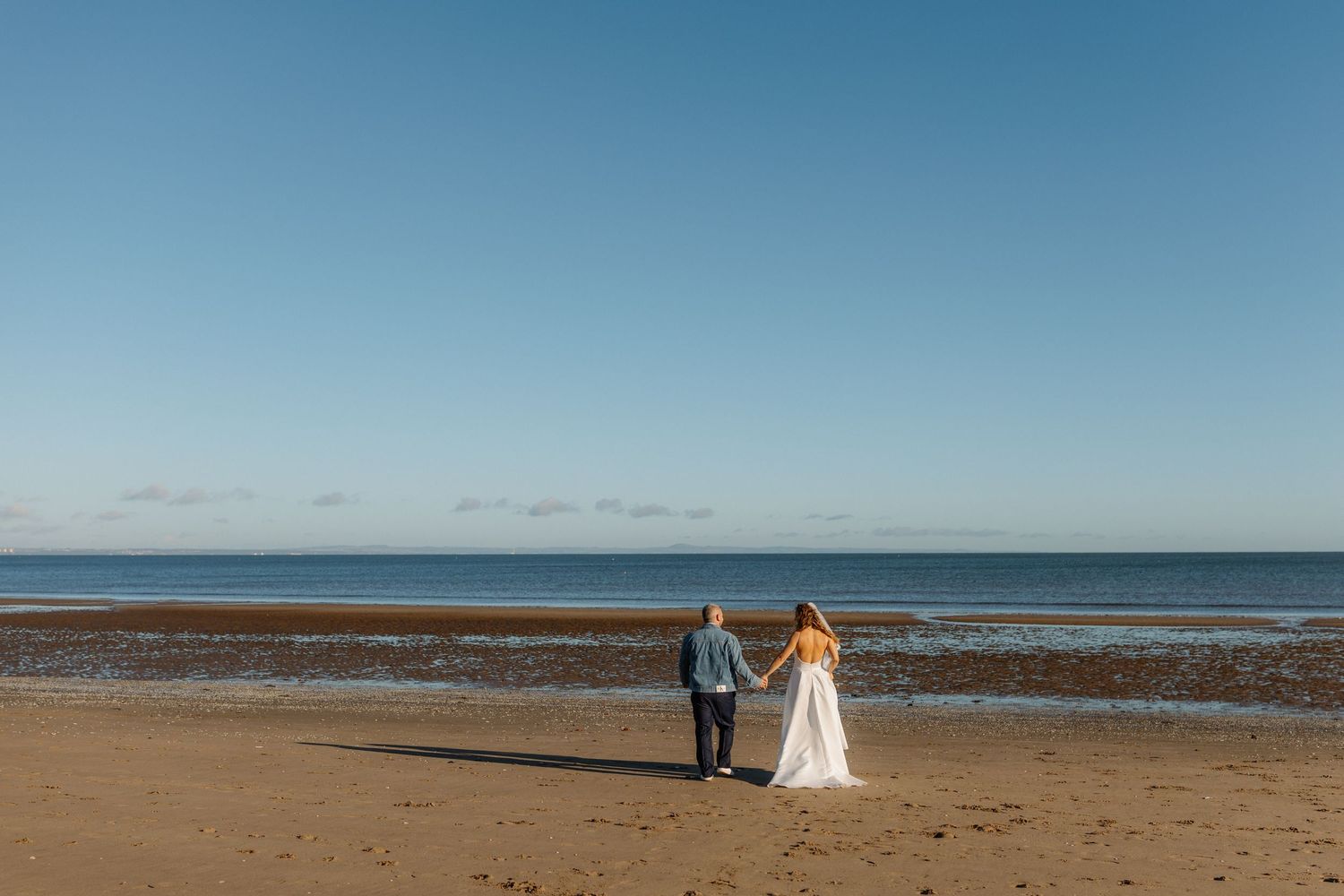 A scenic coastal wedding photoshoot on a beach with dramatic ocean views and blue skies in the background.