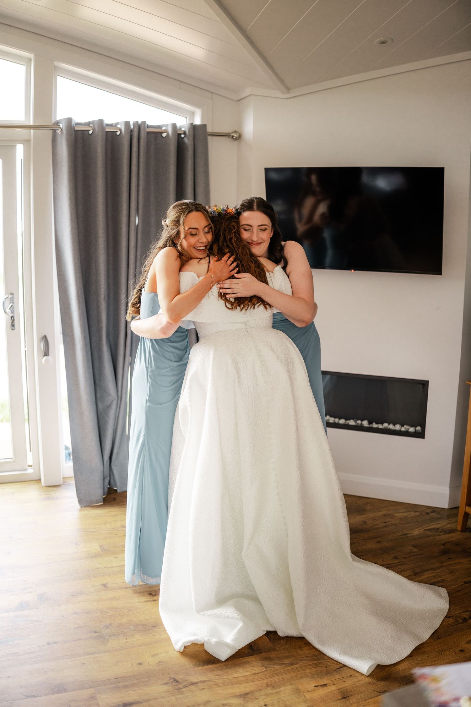 Emotional moment of dress fitting in a bright modern room with hardwood floors.