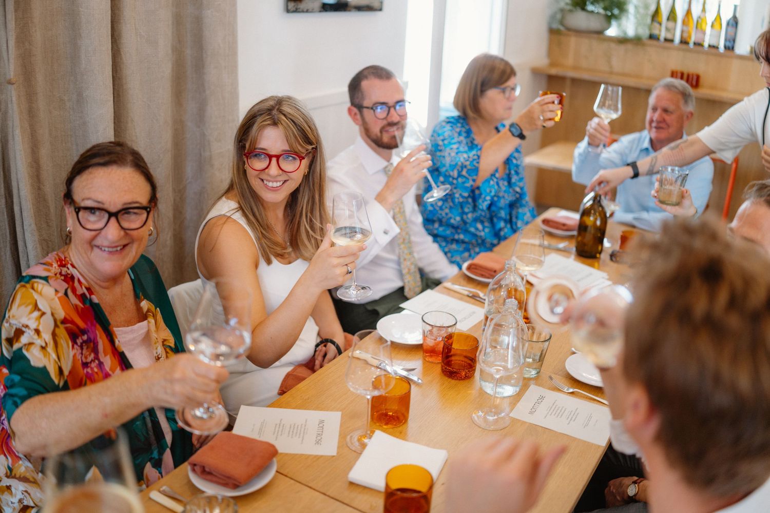 Friends gathered around a table enjoying drinks and conversation at a casual gathering.