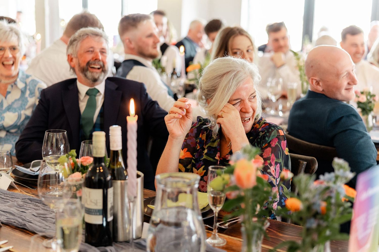 Wedding guests enjoying dinner and conversation at decorated reception tables.