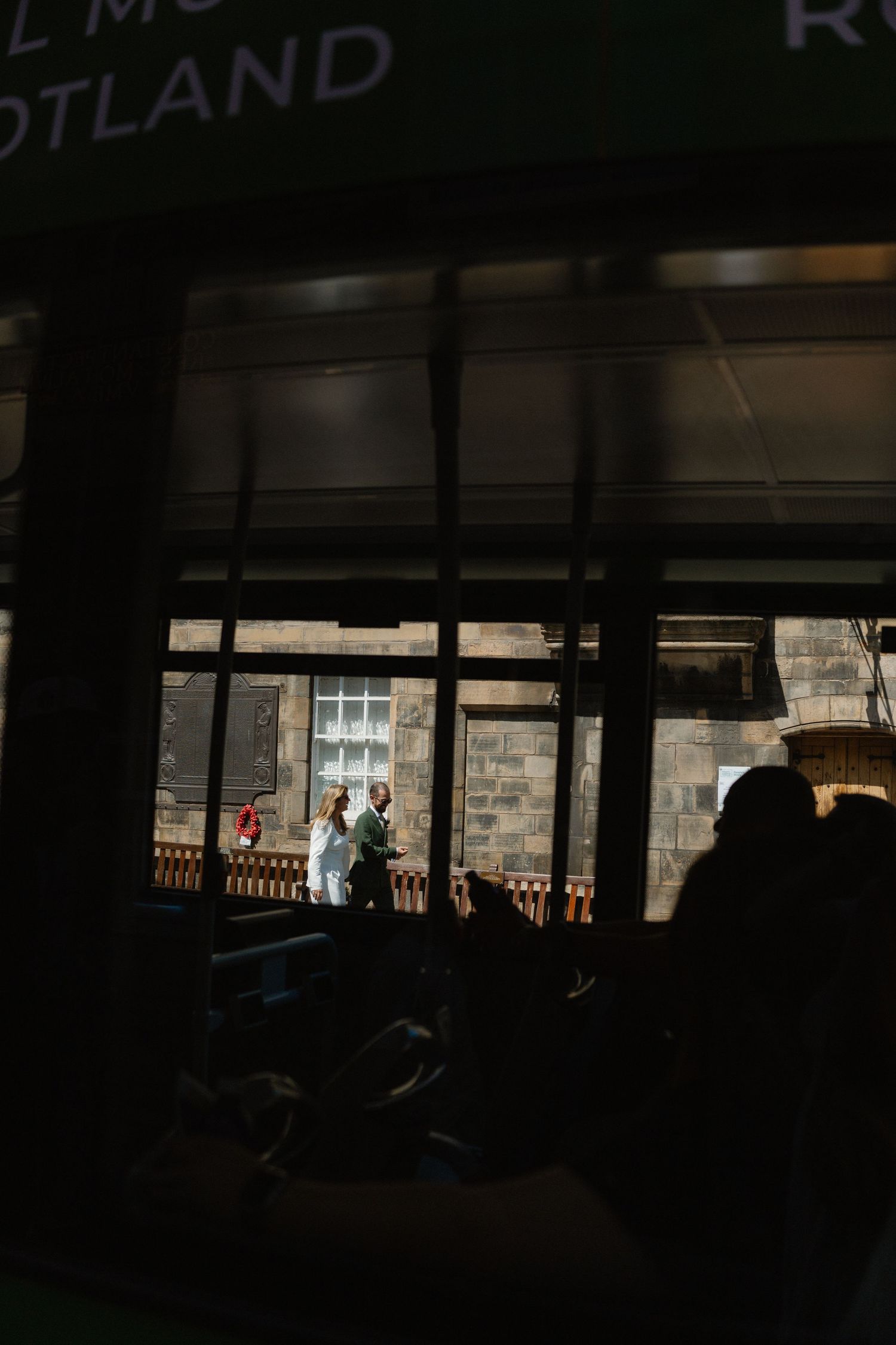 Dark silhouettes visible through windows of a dimly lit interior space.