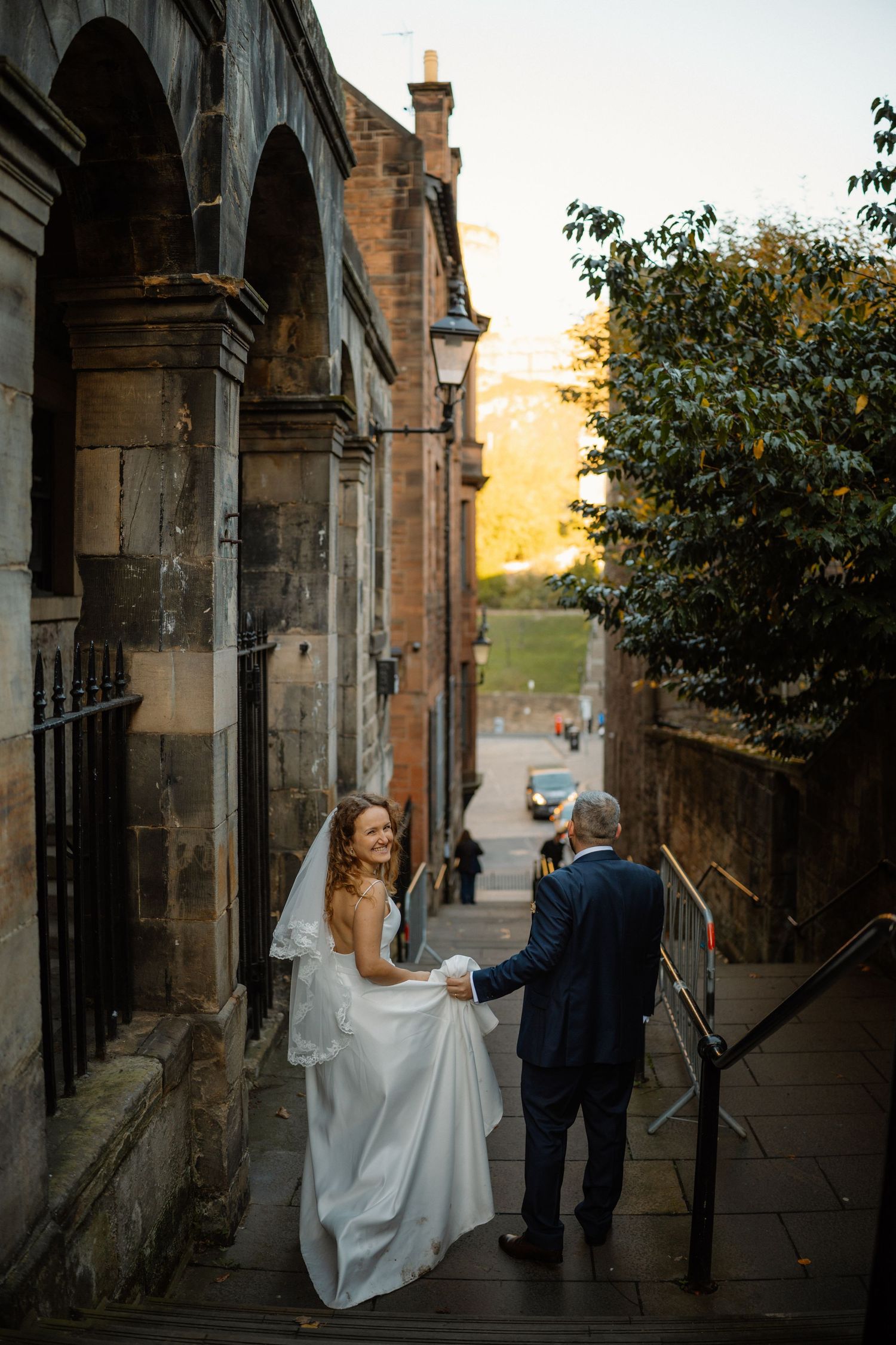 A couple descending stone steps at sunset near historic architecture.