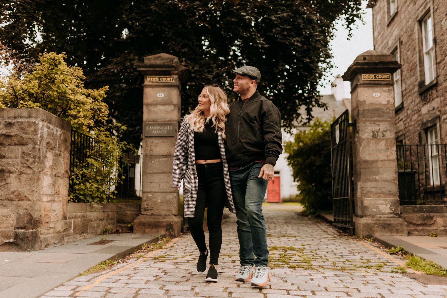 Couple walking together along stone pathway on autumn day.