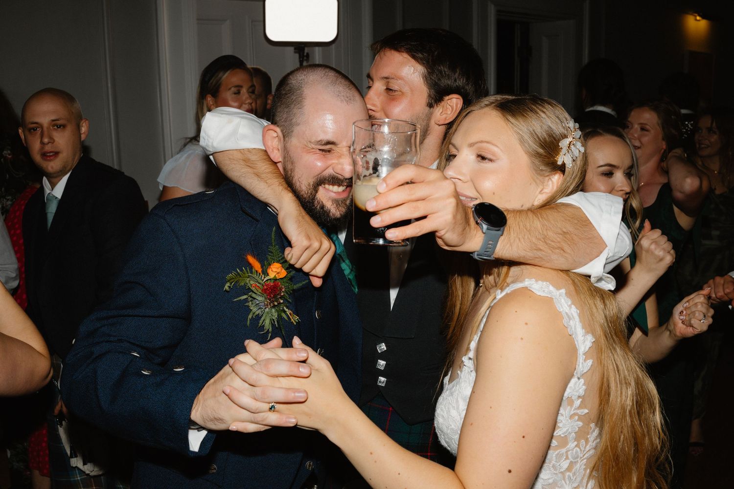Bride and groom share a joyful moment drinking together on the wedding dance floor.