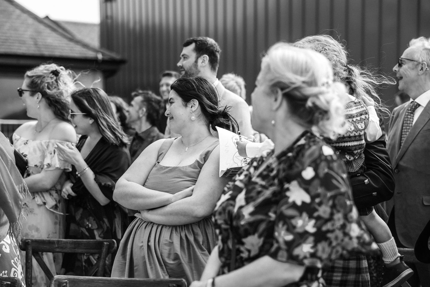 A crowd of wedding guests reacting with emotion during an outdoor ceremony.