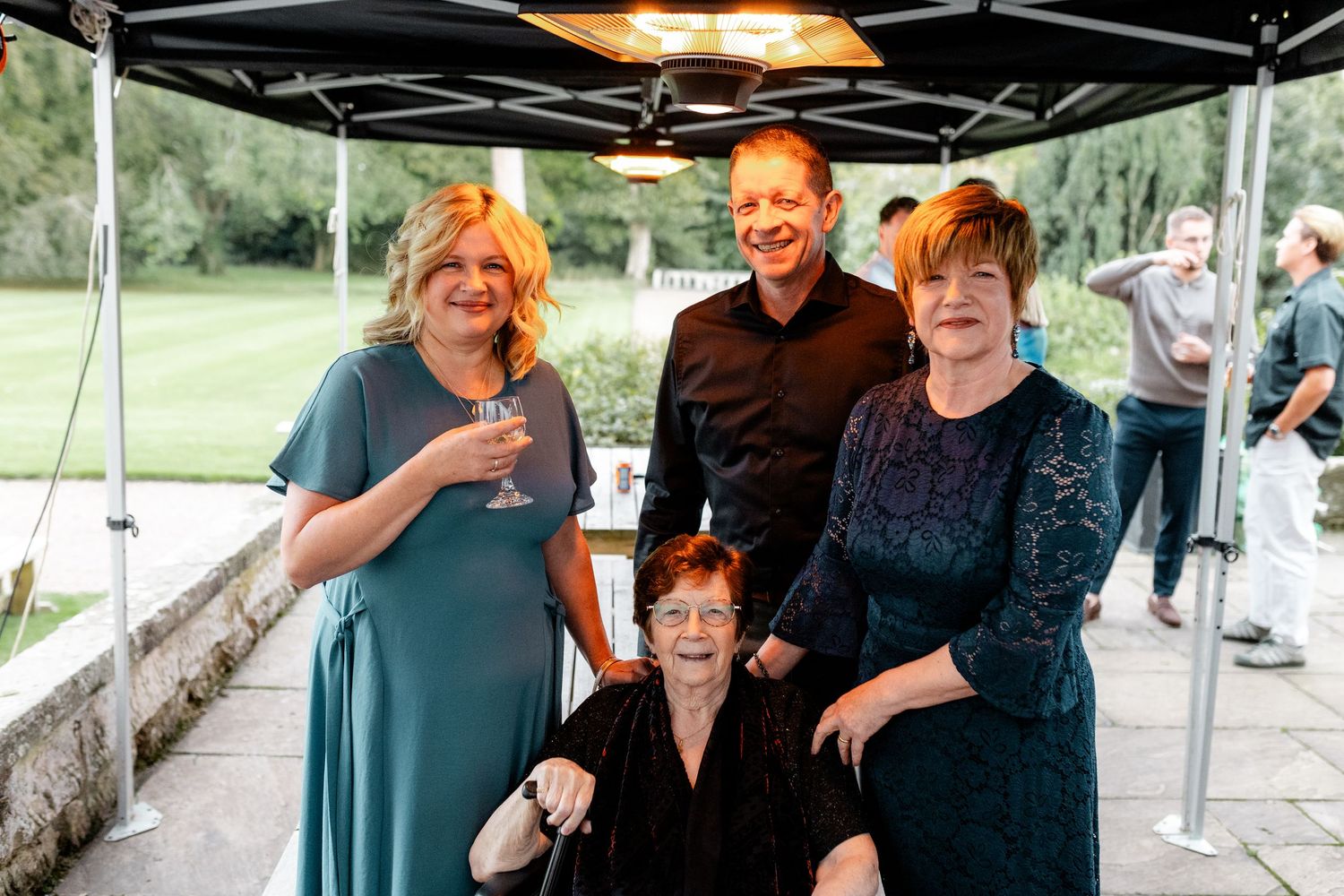 Wedding guests enjoying drinks and conversation under an outdoor tent.