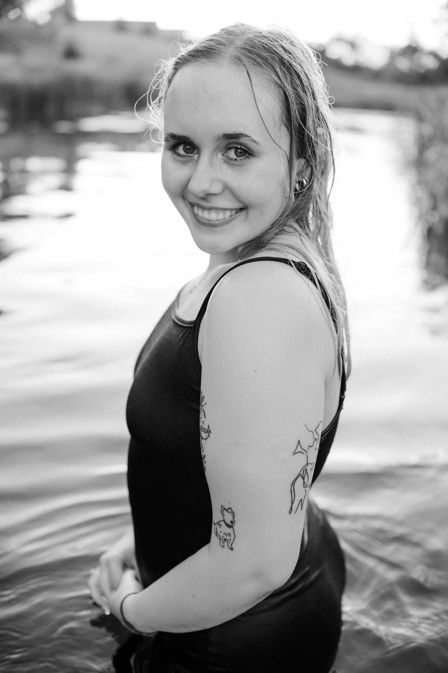 Portrait of someone in black swimwear showing tattoos in black and white photography.