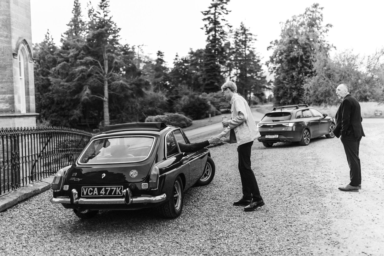 Vintage cars parked along a driveway during what appears to be a special event.
