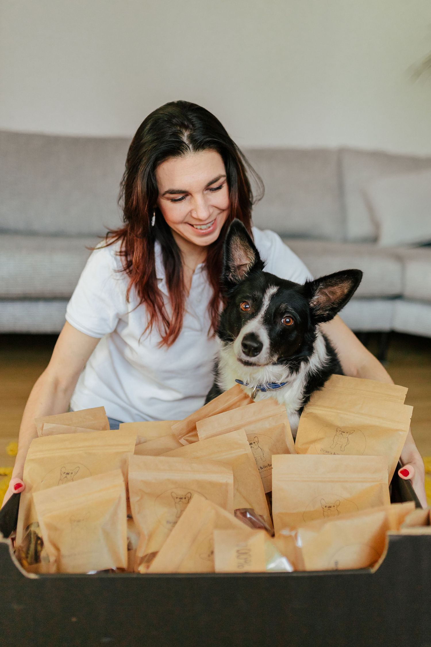 Collection of natural dog treat bags displayed on wooden surface with dog.