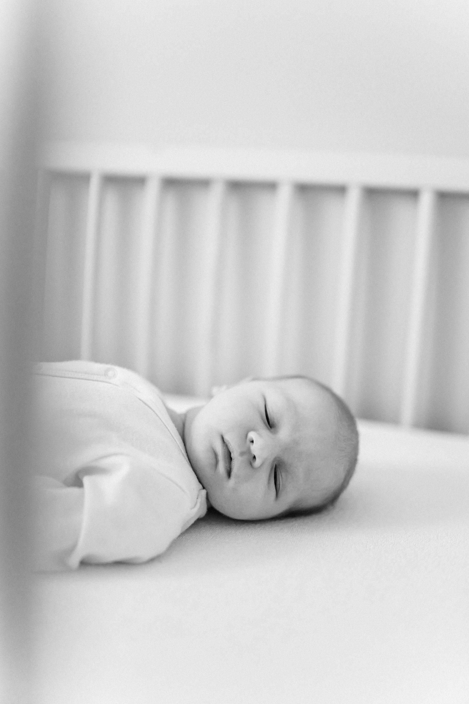 Peaceful sleeping baby in white crib with soft focus black and white photography.