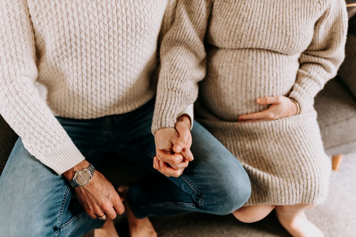 People sitting close together wearing cozy neutral sweaters.