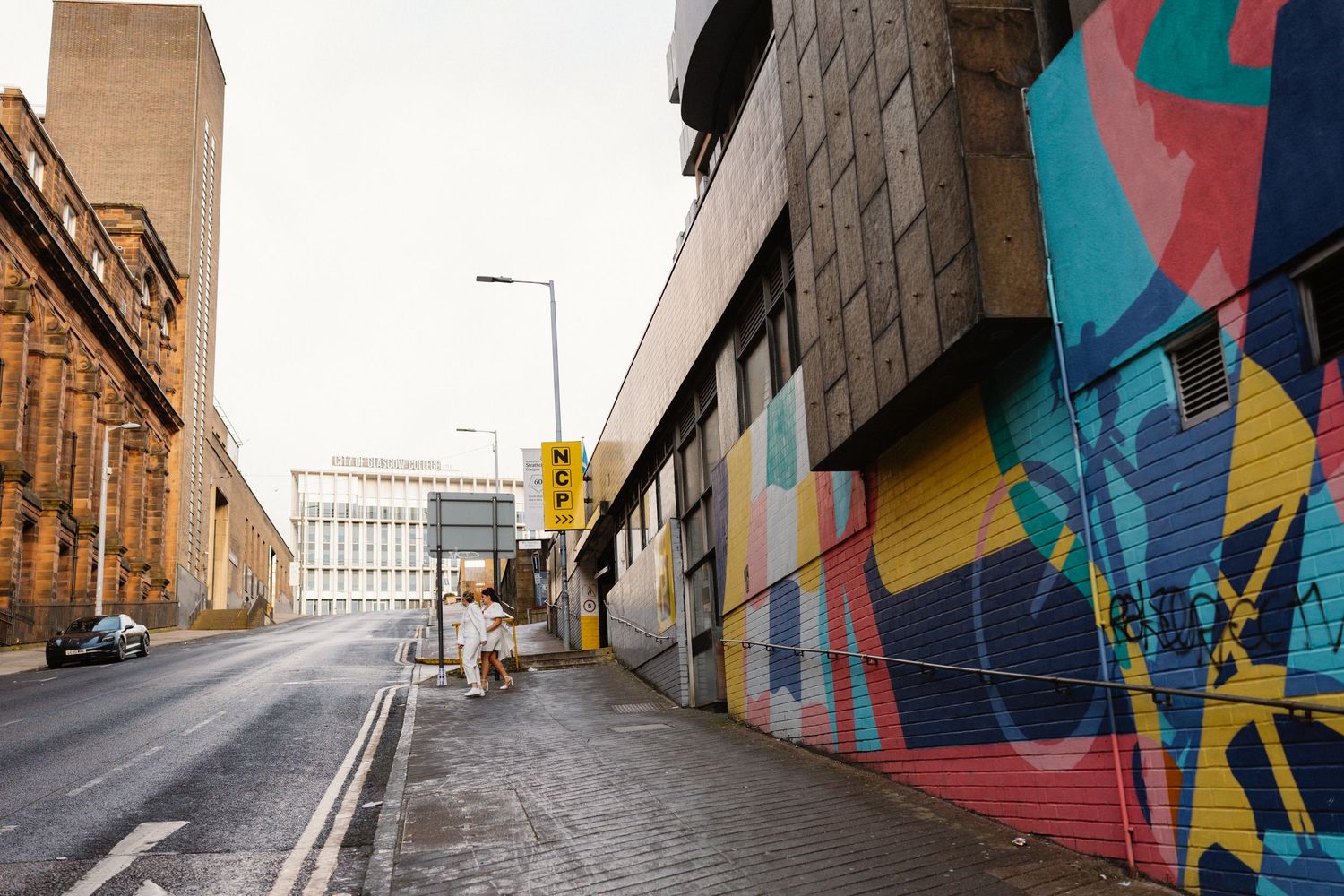 Urban alley with colorful street art mural on building wall, quiet city street with classic architecture in background.