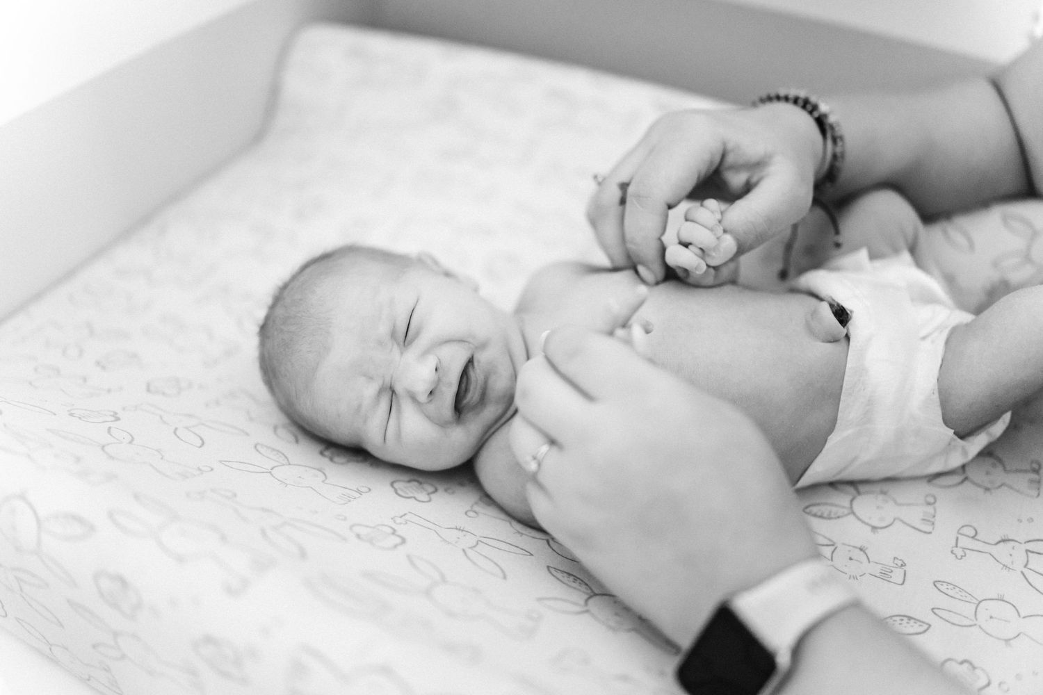 Newborn baby resting peacefully on white textured bedding.