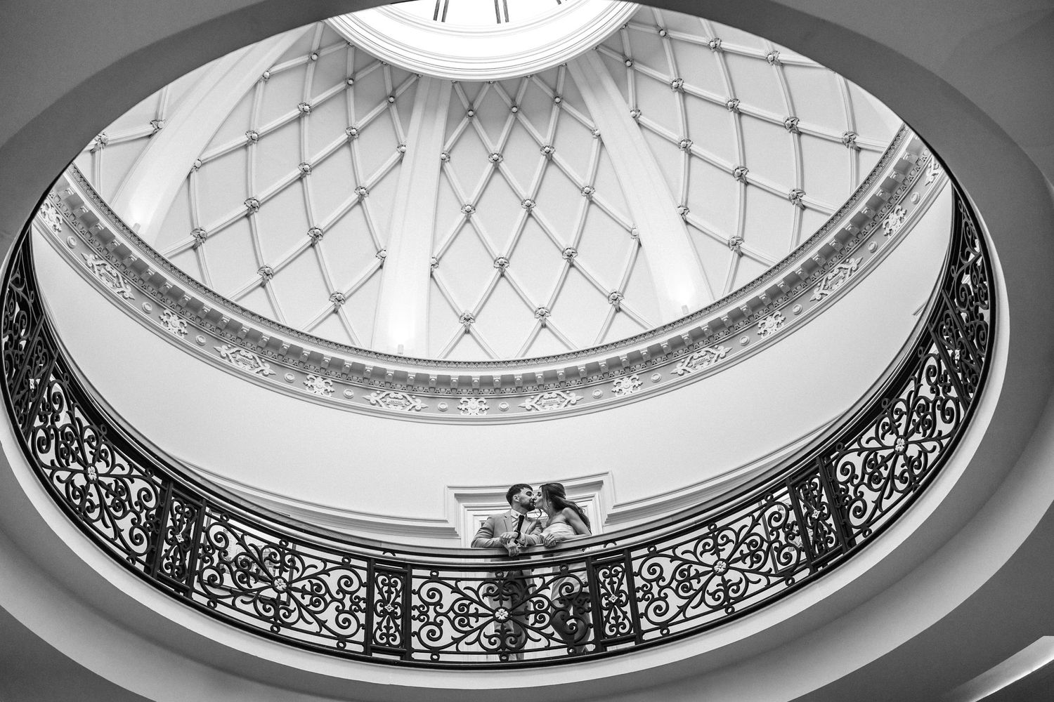 Black and white view of a circular domed ceiling with intricate ironwork patterns.