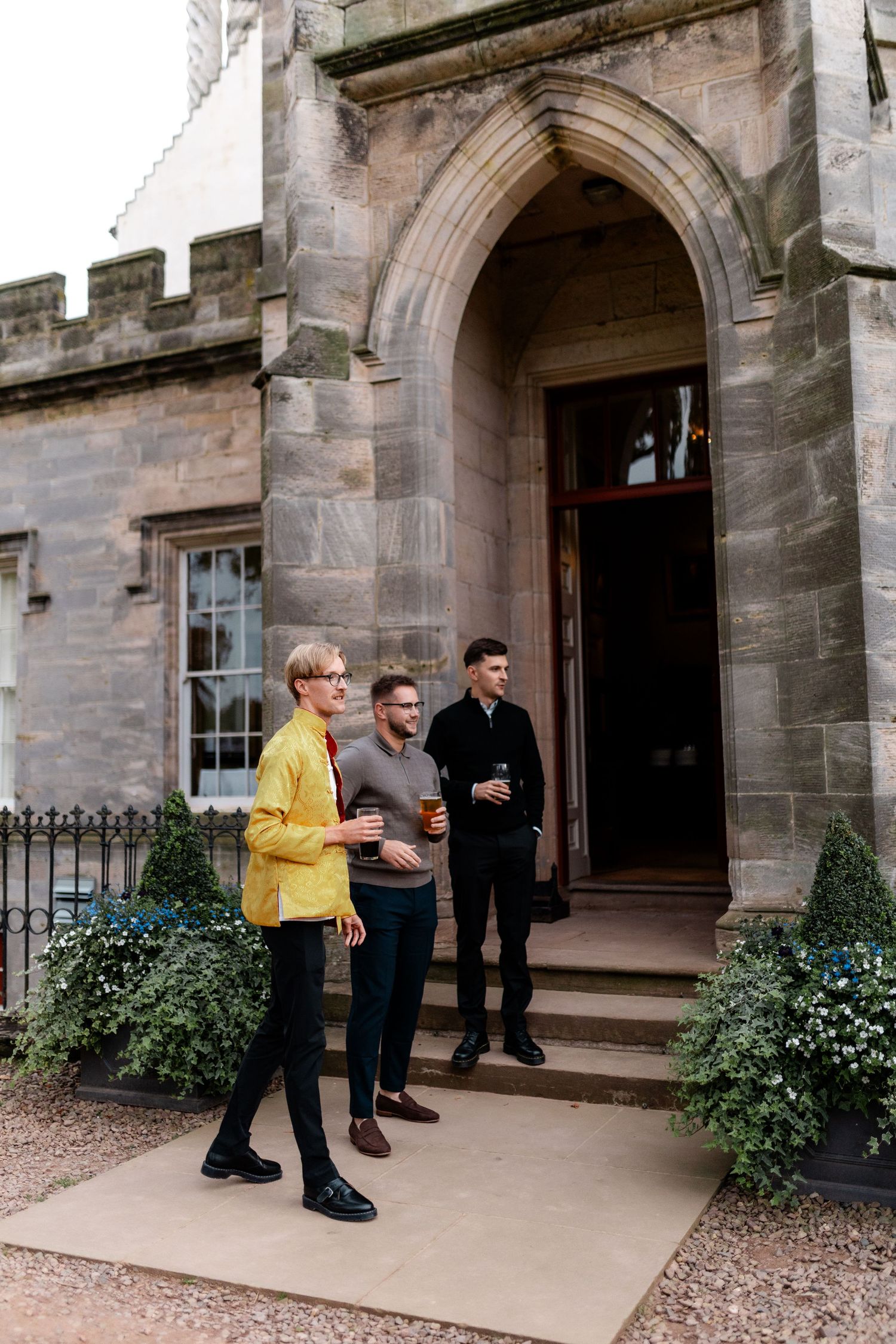 Group gathering outside a grand stone building with arched doorways and classic architecture.