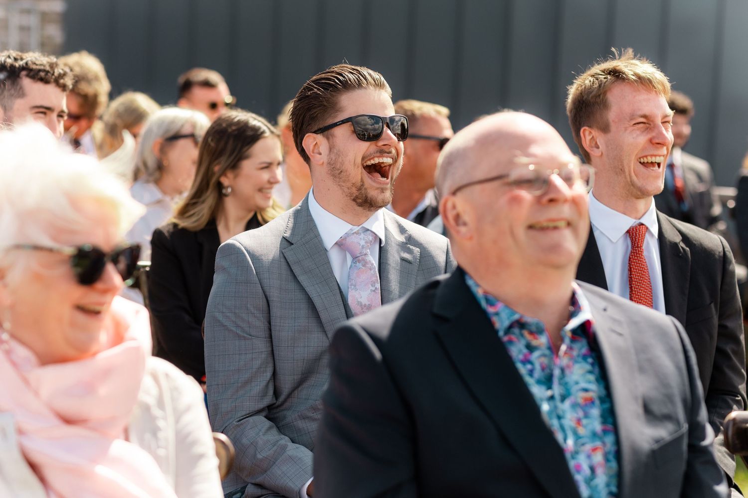 Wedding guests sharing joyful laughter during an outdoor celebration.