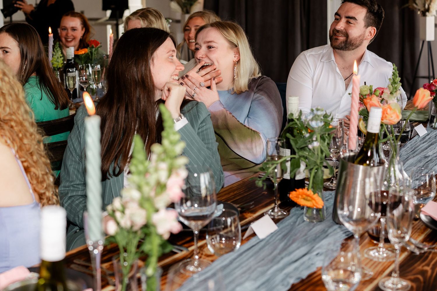 Wedding reception guests sharing laughter and joy at decorated dining tables.