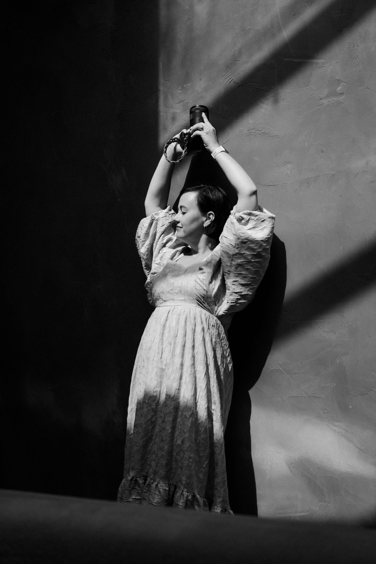 A dramatic black and white photo of a dancer in a vintage dress posing gracefully in a beam of light.