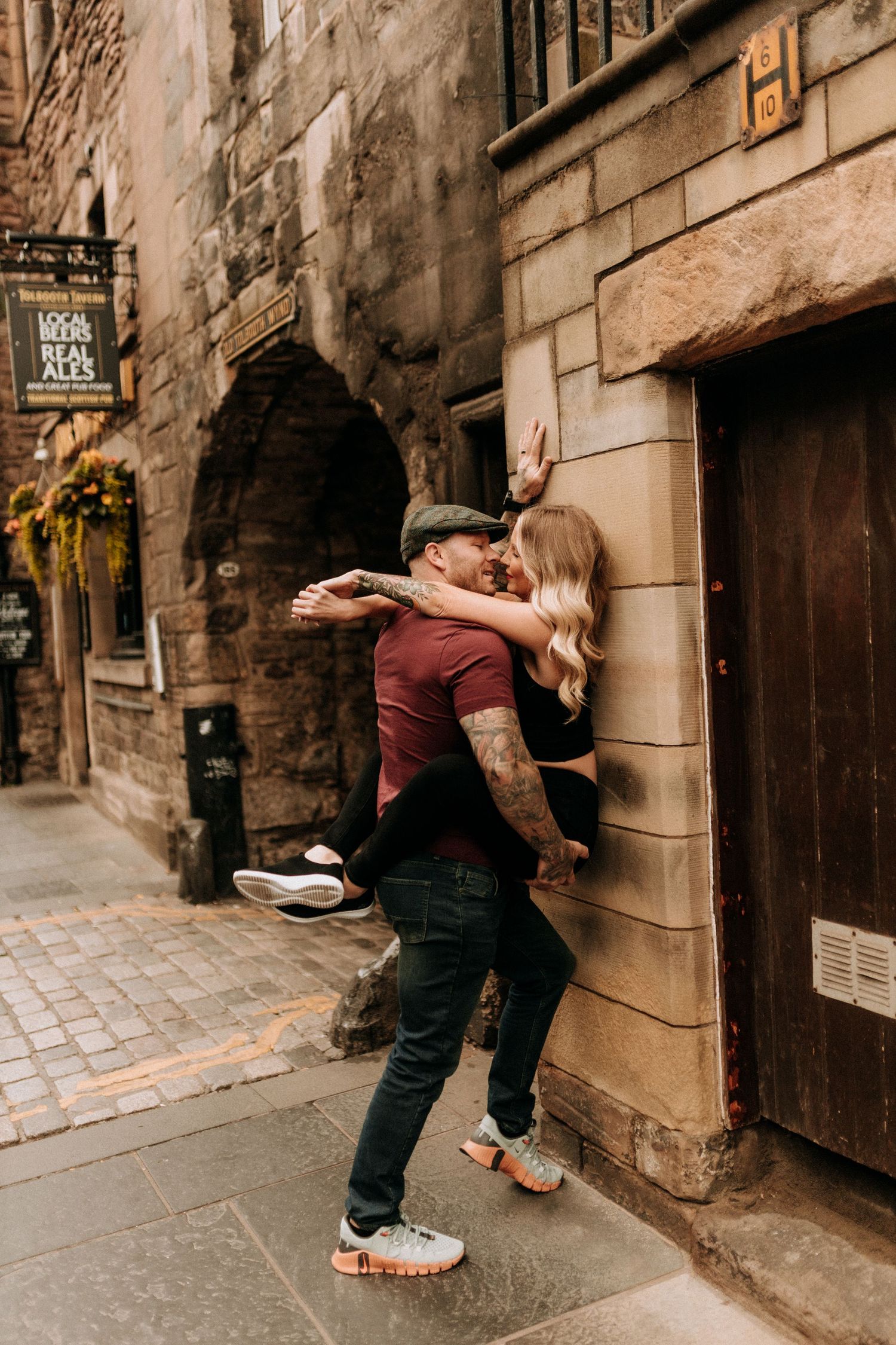 Romantic couple dancing and embracing along a historic cobblestone street with stone buildings.