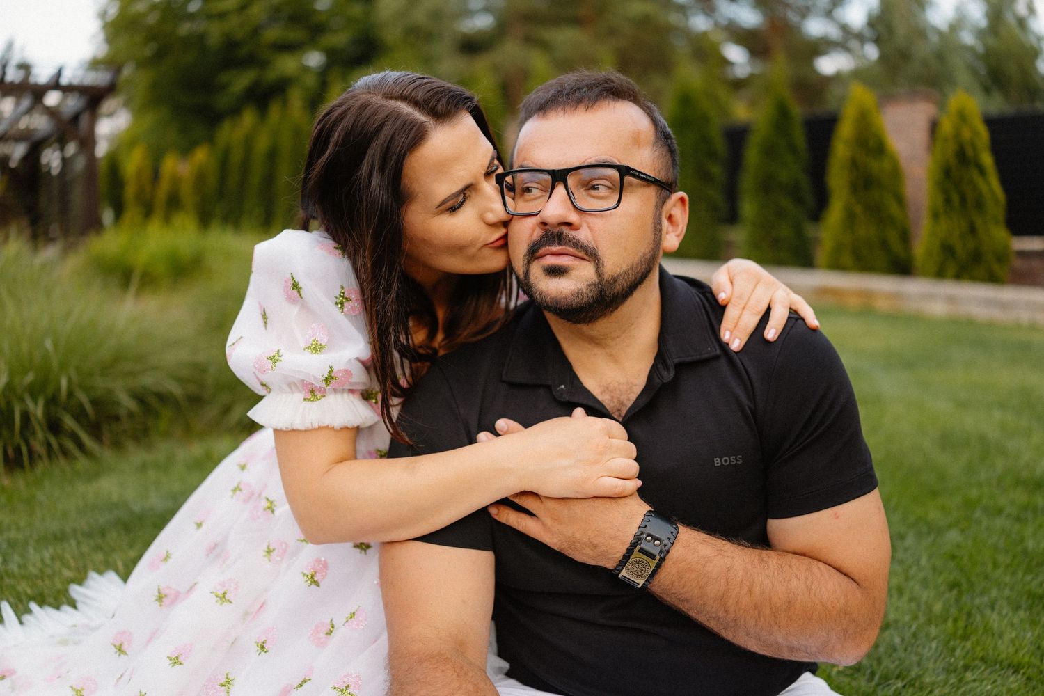 Couple embracing on green lawn during outdoor photo session.