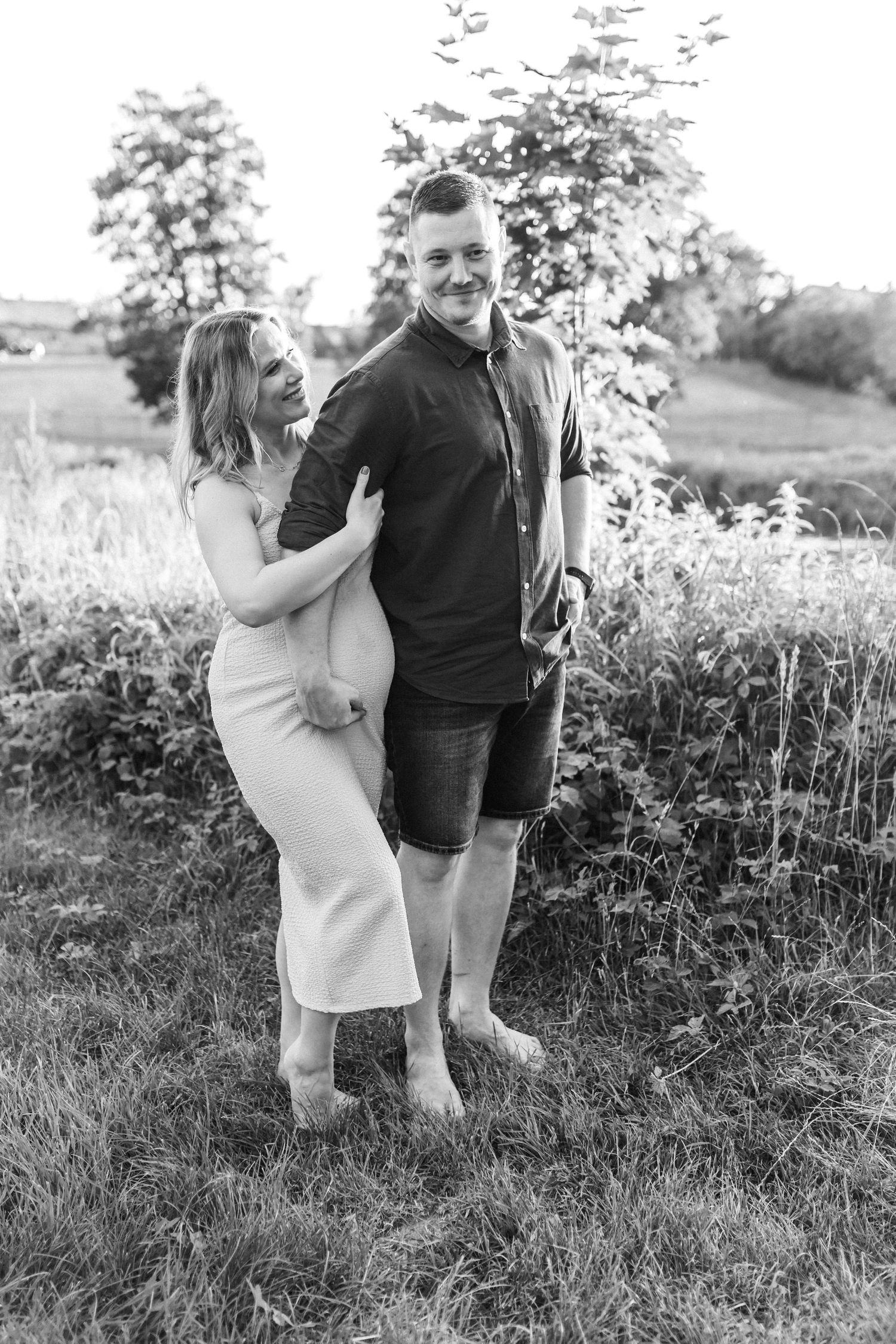 Couple sharing playful moments in black and white photography outdoors.
