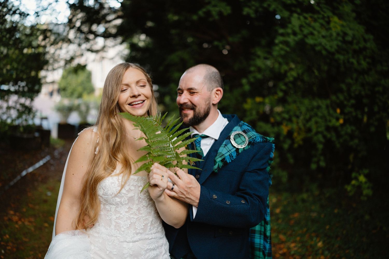 A couple shares joyful moments together in a lush outdoor garden setting during a wedding photo session.