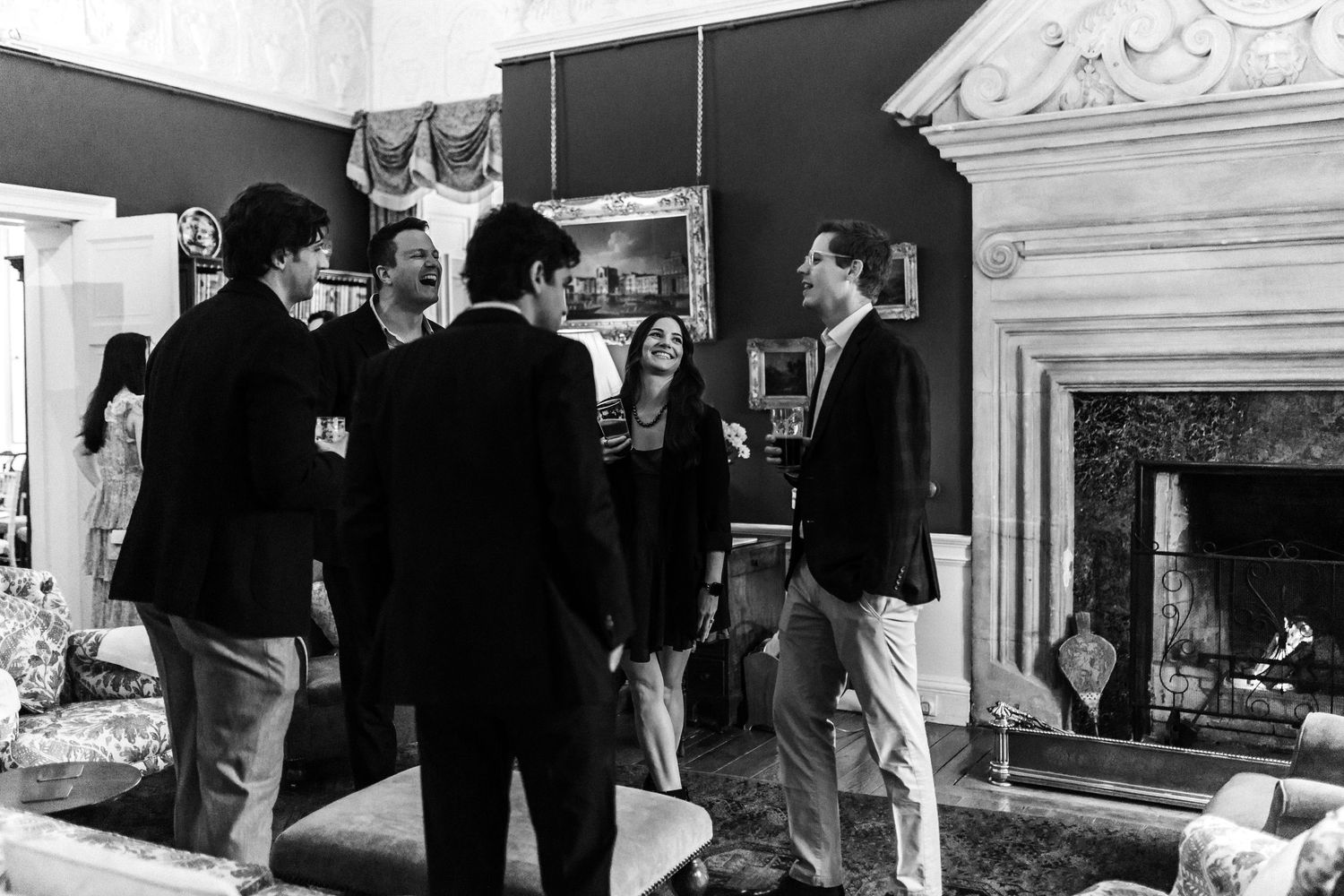 Black and white photo of people gathered in an elegant room with ornate decor.