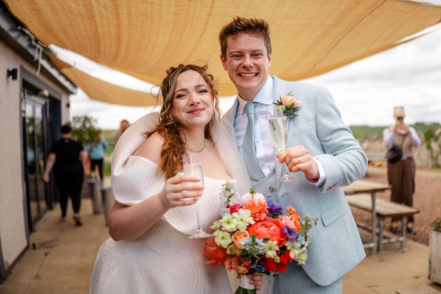 Wedding celebration under beige canopy decorations with coral and white floral arrangements.