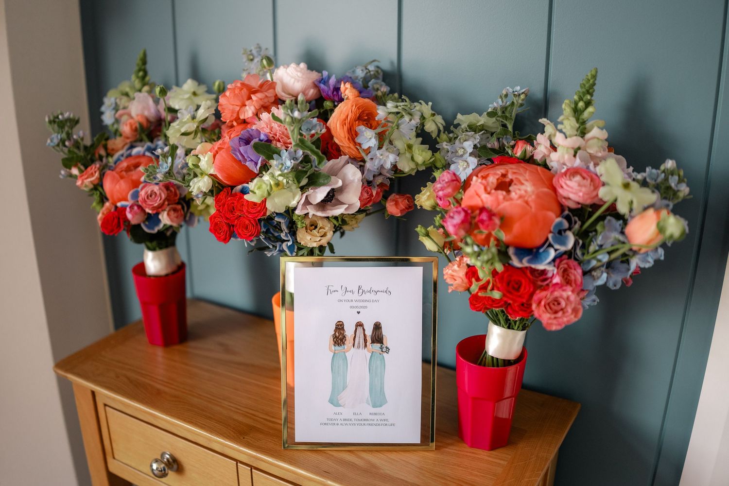 Vibrant floral arrangements with coral and red blooms displayed on wooden furniture.