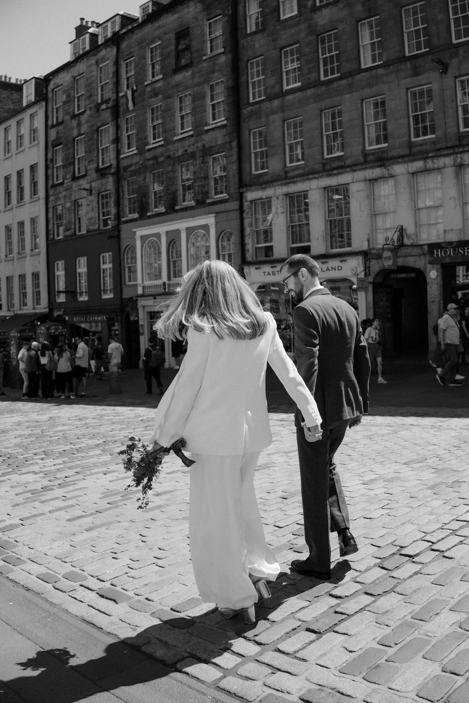 A couple walking on historic cobblestone streets in Edinburgh.