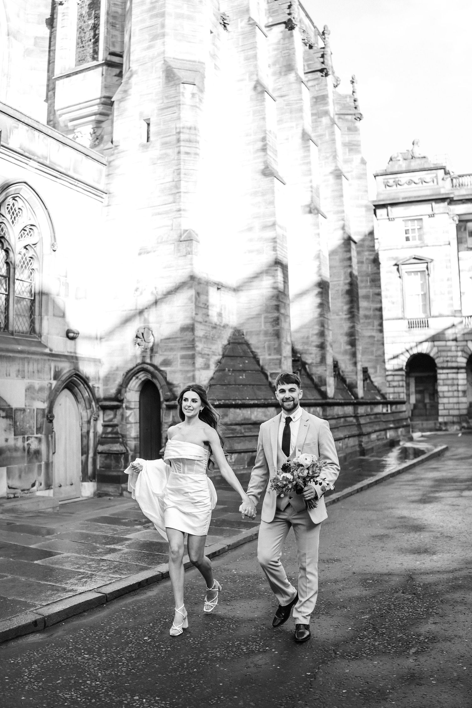 Black and white street scene with people walking along historic buildings.