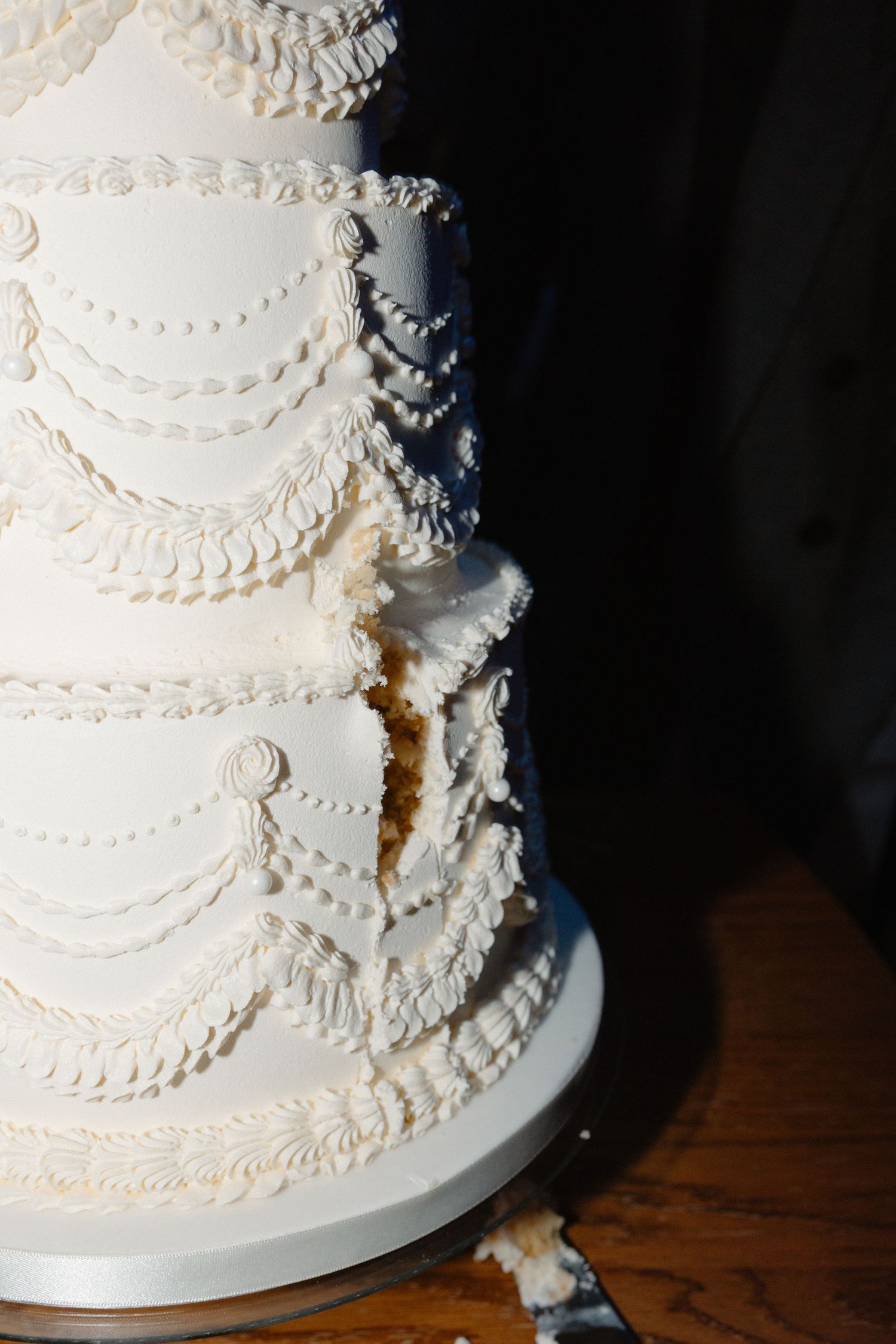 Close-up detail of an elegant white wedding cake with intricate piped lace patterns.