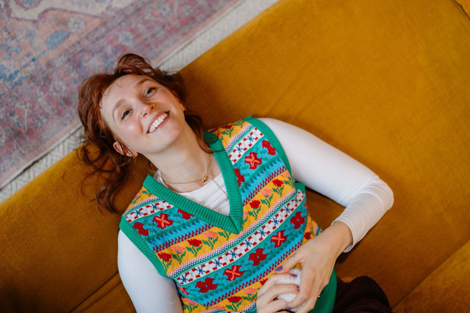 Relaxed poses on a yellow couch with decorative pom poms scattered around.