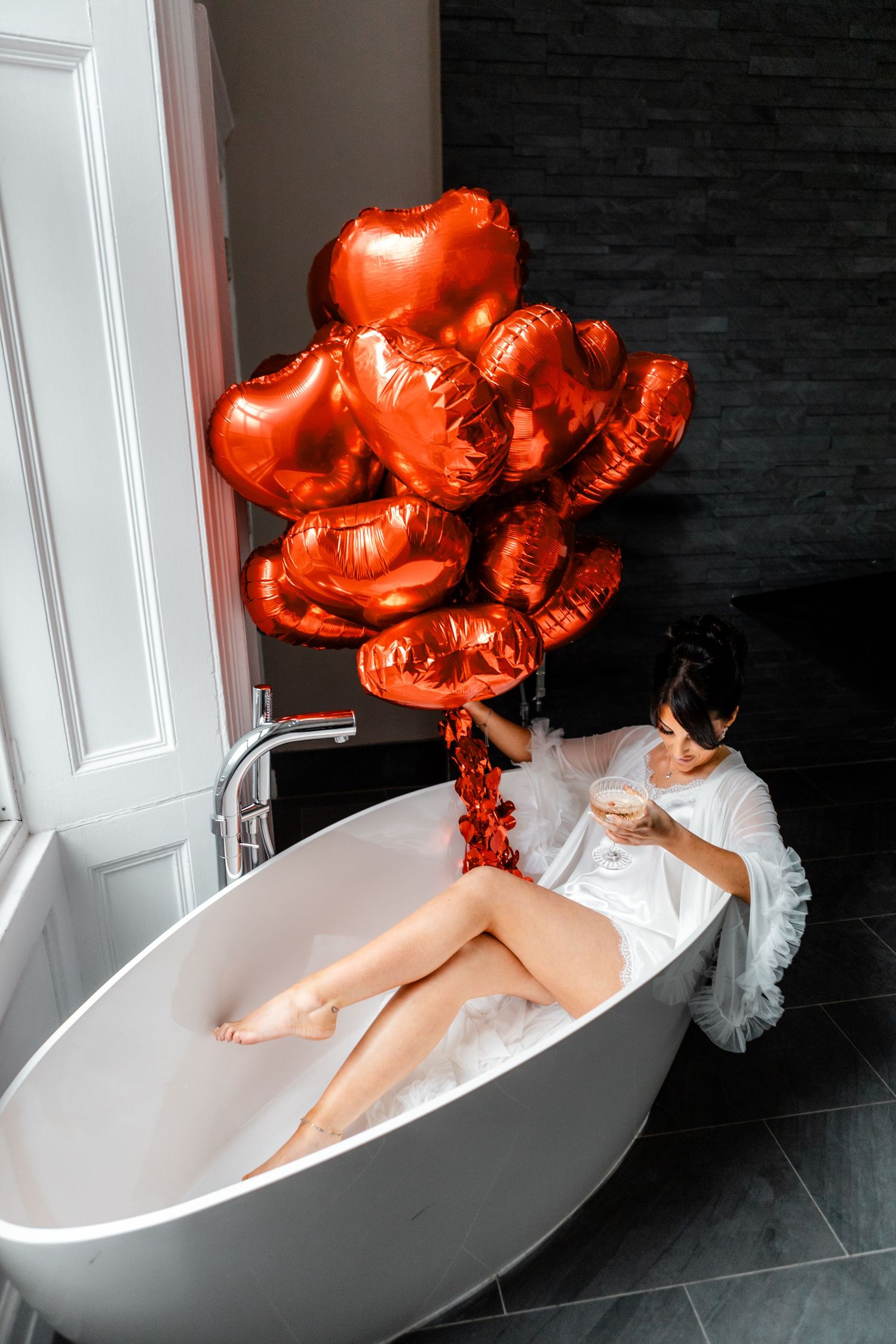 Bathtub scene with red heart-shaped balloons creating a romantic atmosphere.