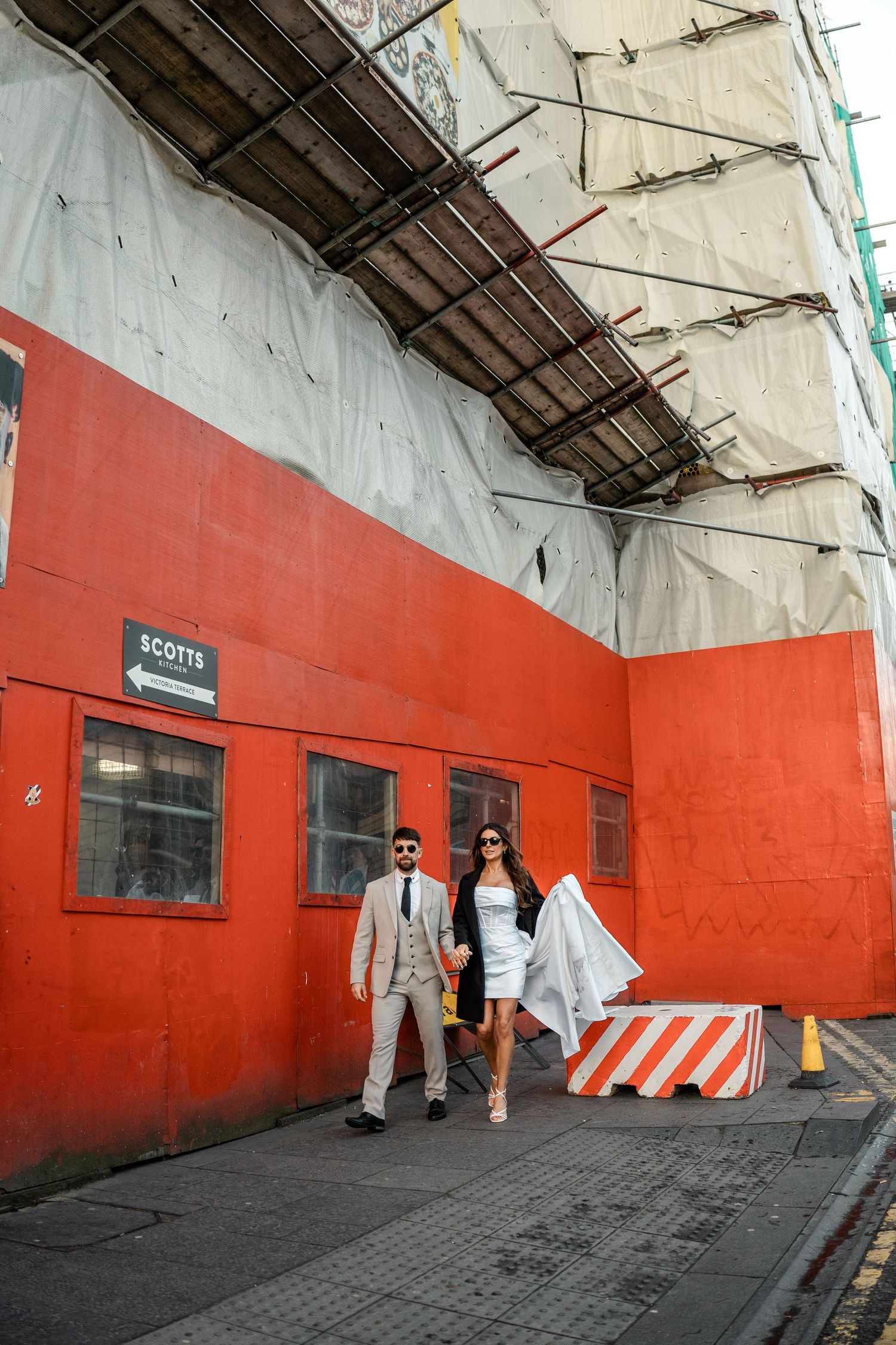Wedding photo series against a striking red wall in an urban setting.