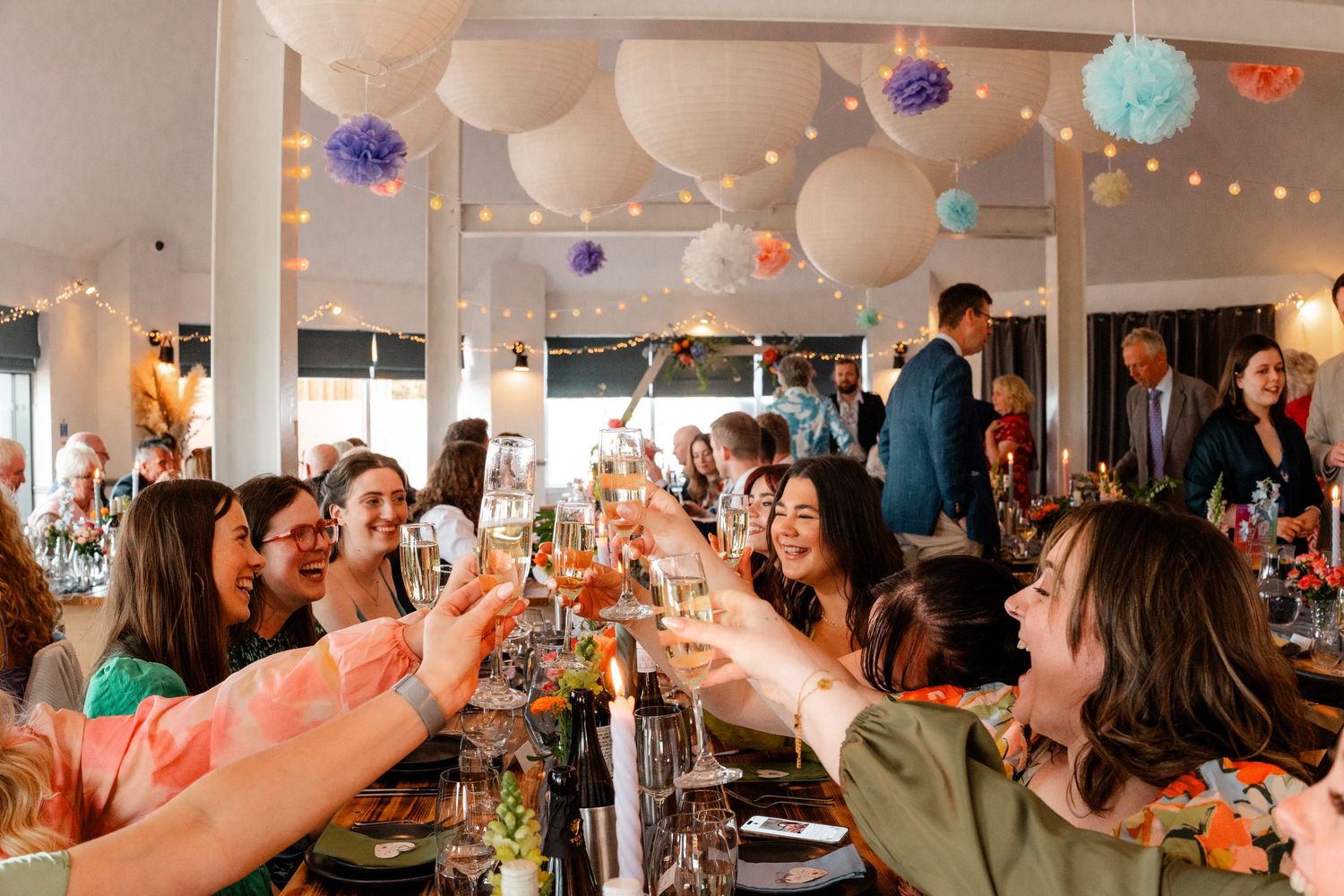 Wedding reception room decorated with colorful paper lanterns and string lights.