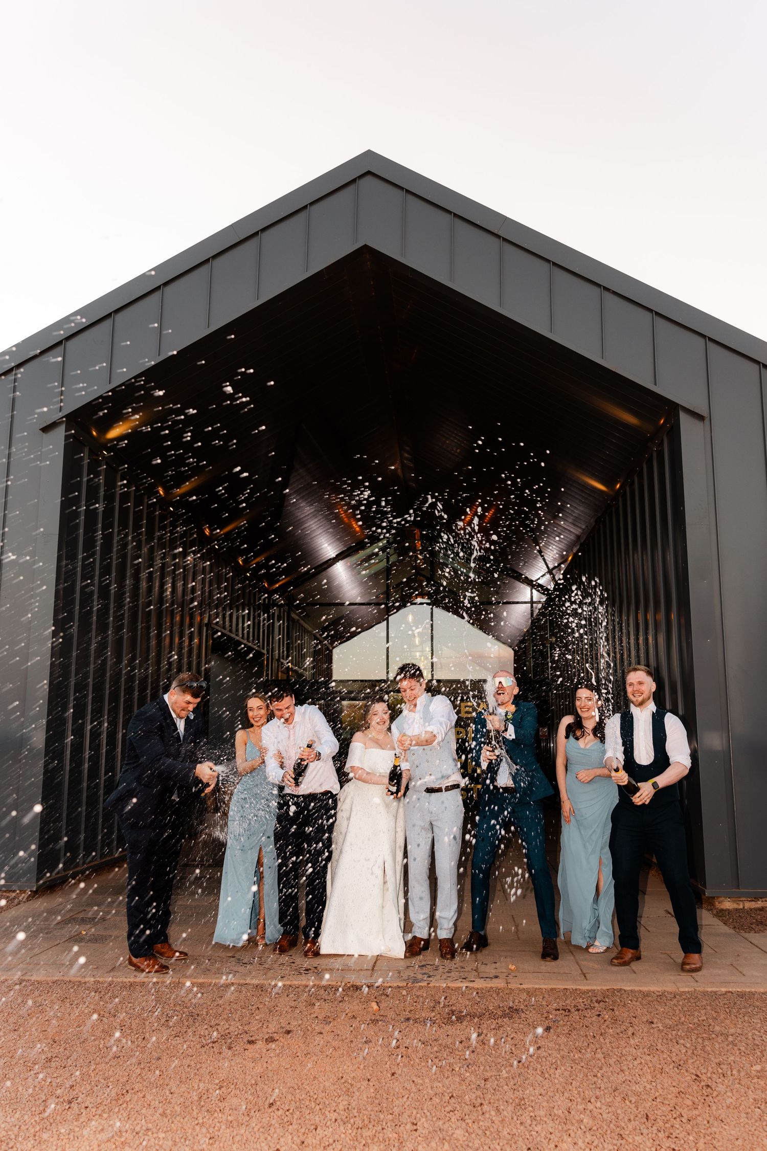Wedding bride and groom champagne spray with friends, Whitekirk Hill, Whitekirk, North Berwick