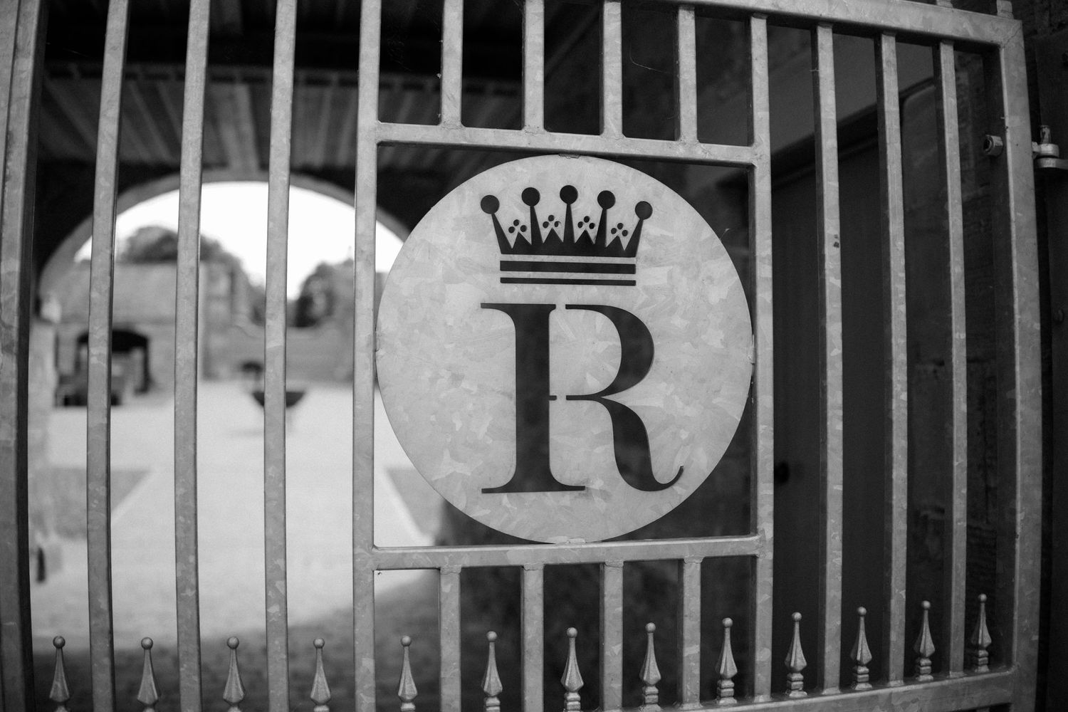Black and white architectural detail of ornate iron railings and crown motifs against a light background.