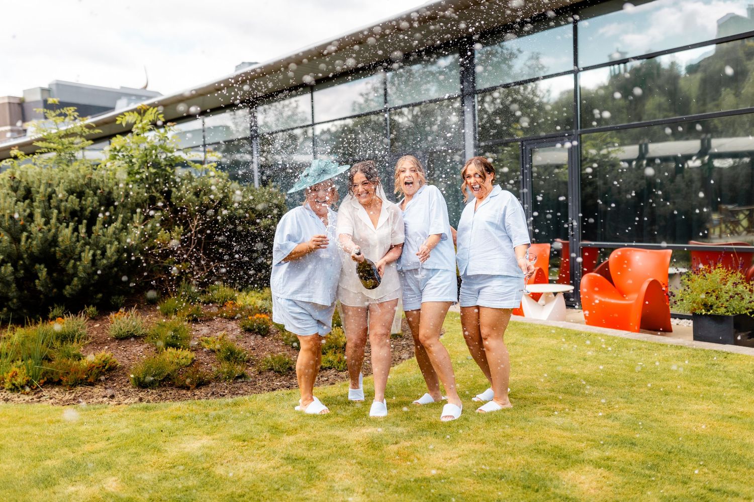 Bride champagne spray with friends, wedding Glass House Edinburgh, Scotland,