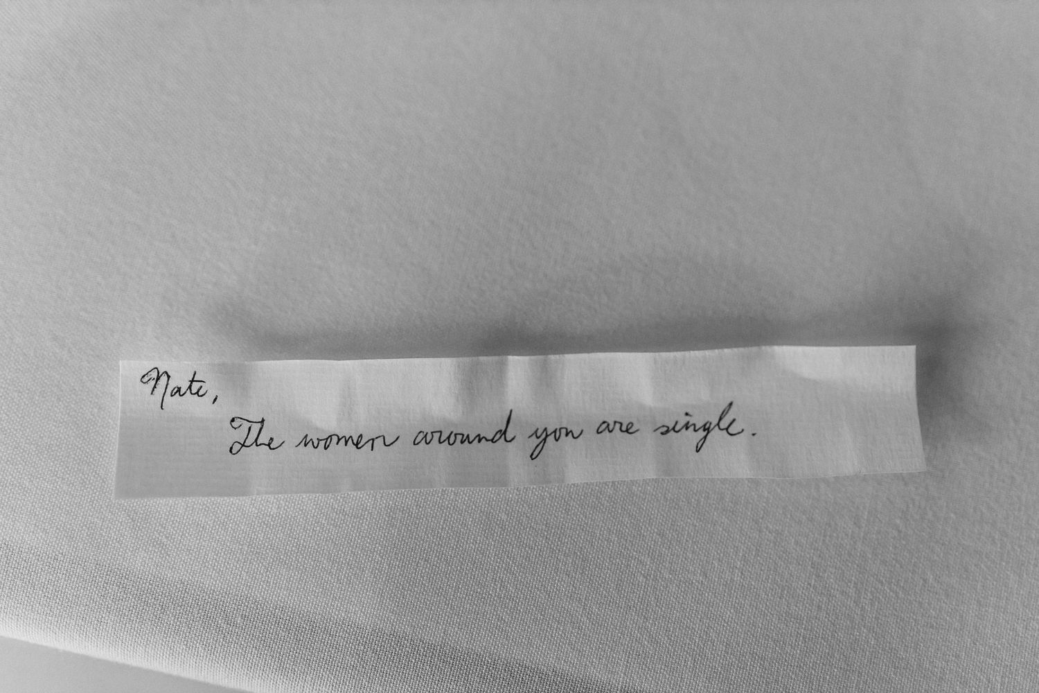 Handwritten note on white paper against a gray background.