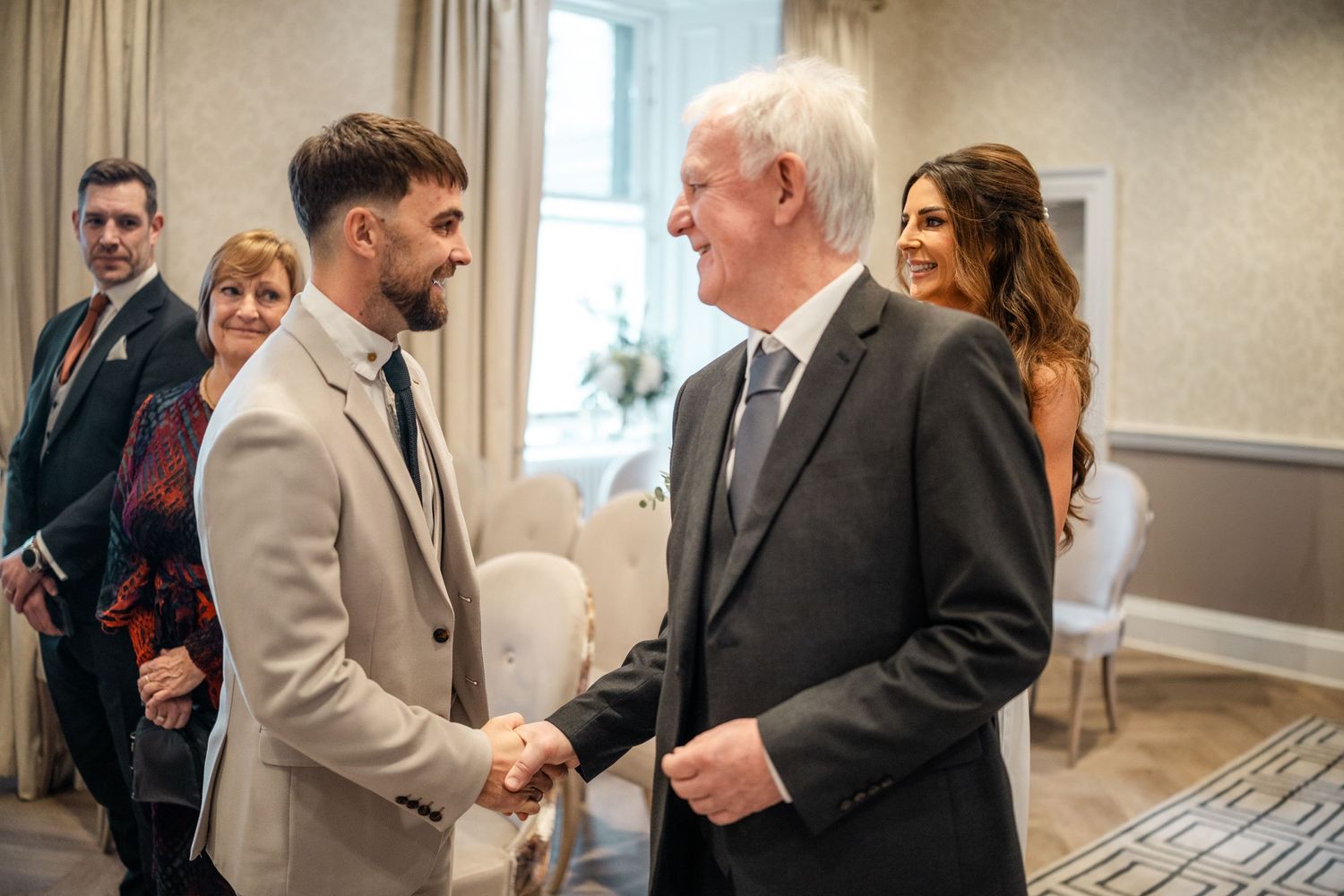 Wedding guests mingling in formal attire at an elegant indoor reception.