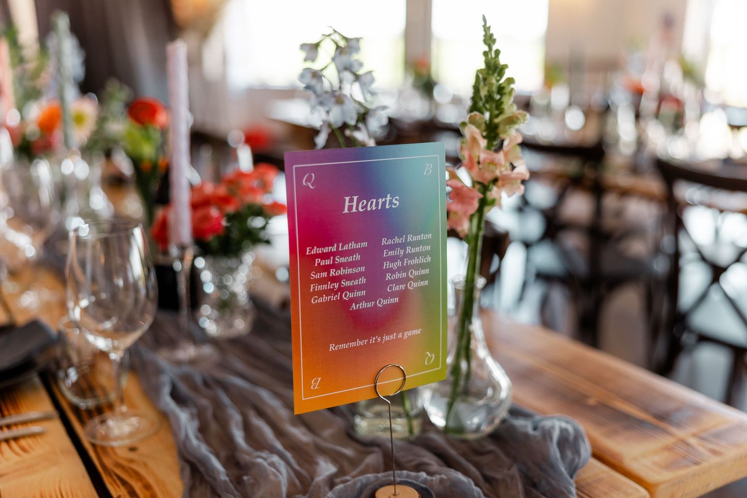 Wedding reception table setting with rainbow-colored menu card and floral centerpiece.