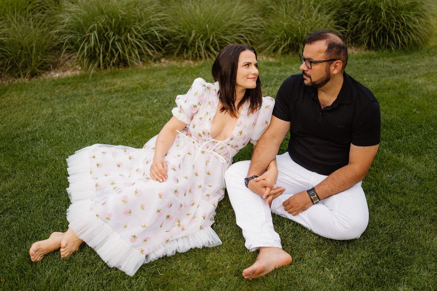 Casual outdoor couple's photoshoot on grass with natural garden backdrop.