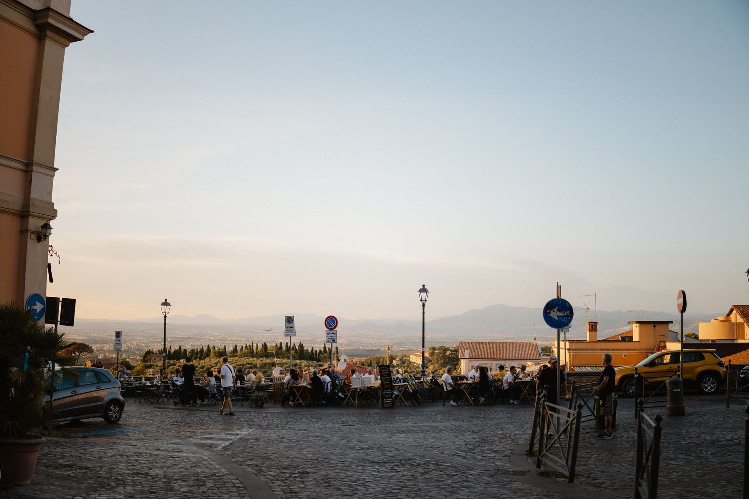 Panoramic coastal view with parked cars and seaside promenade at sunset.